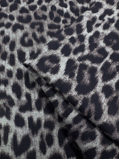 Close-up of Super Cheap Fabrics' Milano Ponte - 150cm, a heavyweight knit fabric with a black and gray leopard print, featuring irregular spots and a soft, textured finish.