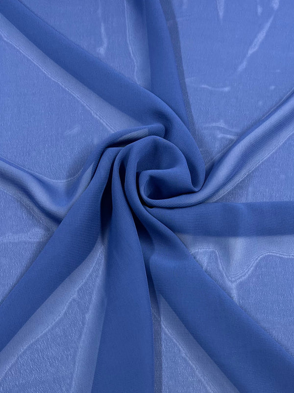 A close-up of the Hi-Multi Chiffon - Denim from Super Cheap Fabrics reveals a sheer blue fabric resembling lightweight denim, arranged in a swirl on a flat surface. Its translucent quality and delicate light reflections create a soft, elegant texture.