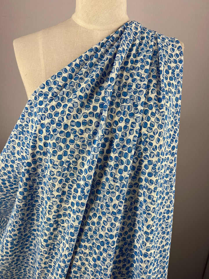 A mannequin displays the vibrant Salt Shrunk Print - Cells fabric by Super Cheap Fabrics. Made from 100% polyester, its intricate design is showcased in a blue leaf pattern against a neutral backdrop.