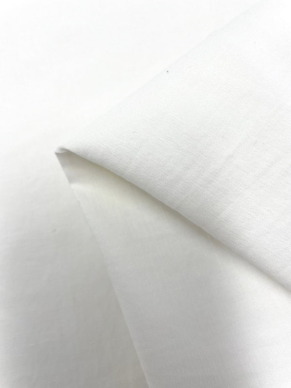 Close-up image of a folded piece of white, medium-weight Stretch Linen Bengaline from Super Cheap Fabrics. The fabric appears smooth and plain, without any visible patterns or textures, and is neatly creased at the fold. The background is also white, blending seamlessly with the fabric.