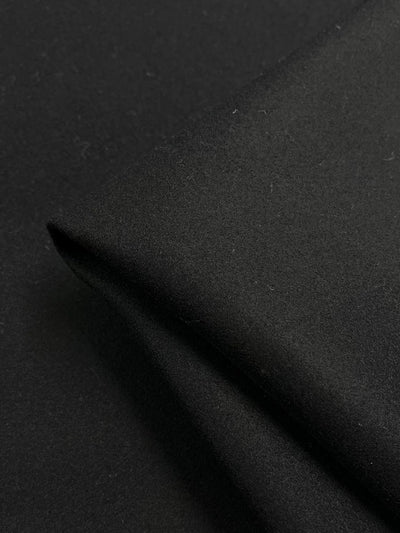 Zoomed-in view of the Virgin Wool - Black - 150cm by Super Cheap Fabrics, highlighting its smooth texture and subtle sheen with a folded corner.