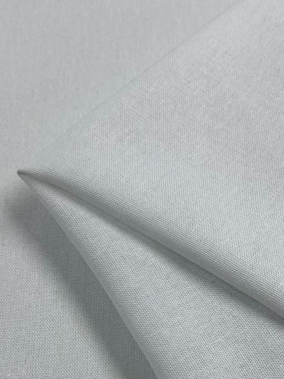 A close-up of the folded Linen Rayon Blend - White - 137cm by Super Cheap Fabrics reveals its smooth texture and fine weave, showcasing a lightweight material with subtle light and shadow interplay.