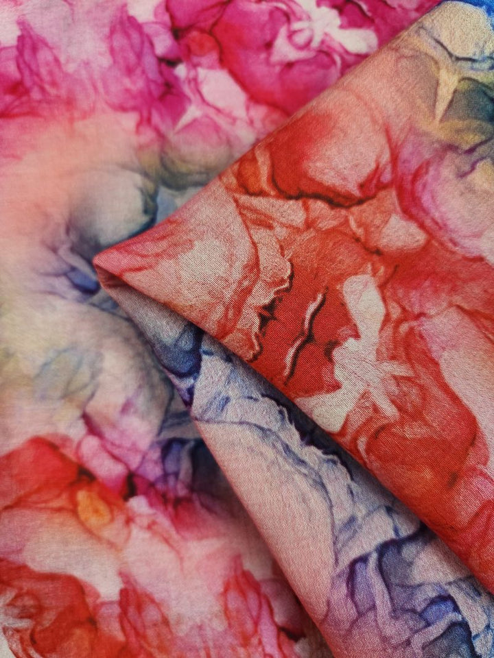 Super Cheap Fabrics presents the Designer Cotton - Roses, a luxurious fabric boasting an abstract floral pattern in pink, red, purple, and blue hues. This 150cm wide textile features a soft, watercolor-like texture that reveals intricate designs and vibrant colors when slightly folded—ideal for luxury sewing projects.