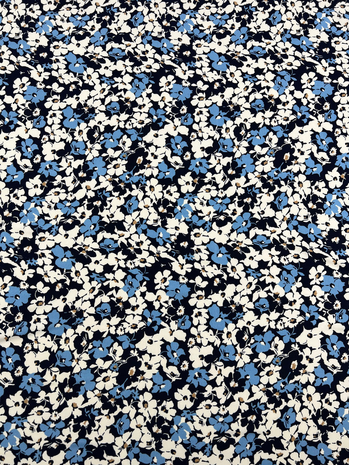 A medium weight polyester spandex fabric with a dense floral pattern featuring small white flowers interspersed with light blue flowers, and a few black floral shapes on a dark background. The design creates a vibrant and visually intricate effect, perfect for tops, dresses, and skirts. This is the Printed Lycra - Blu Density - 150cm by Super Cheap Fabrics.