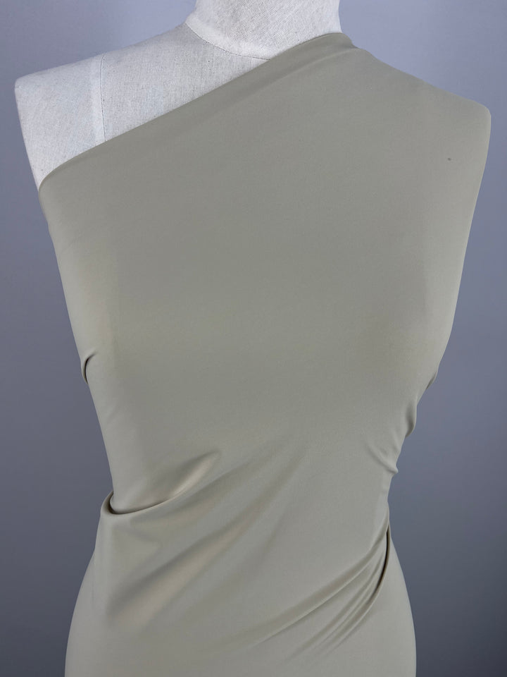 A mannequin exhibits a sleek, one-shoulder dress made from Silver Birch Nylon Lycra, a four-way stretch fabric by Super Cheap Fabrics, set against a gray background.