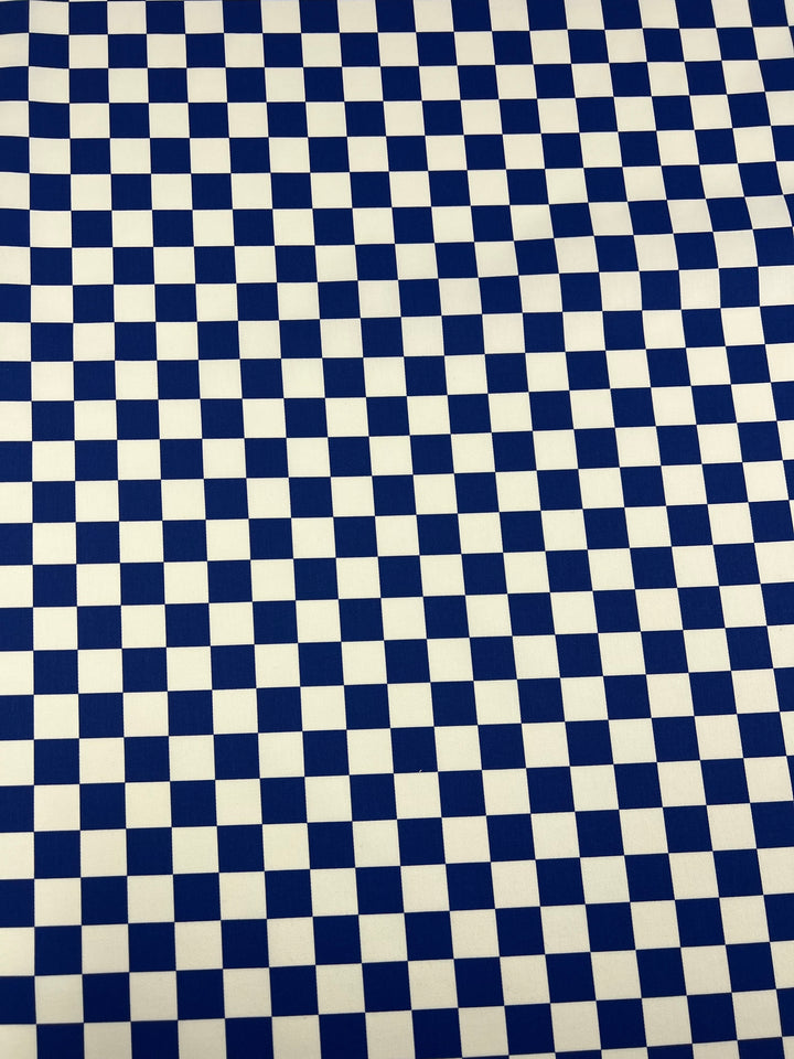 A close-up image of a blue and white checkered pattern. The squares are evenly sized, creating a uniform, grid-like appearance across the entire image. The pattern, rendered in Super Cheap Fabrics' Cotton Drill - Blue Chess - 155cm fabric, boasts a classic, minimalist design with a lightweight texture that adds subtle sophistication.