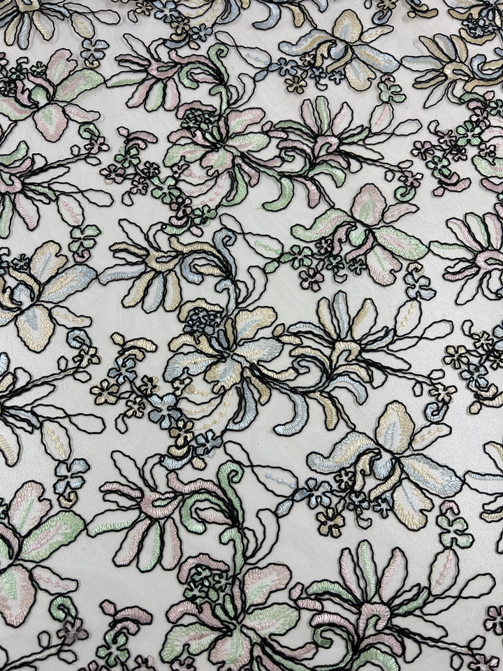 This image shows an intricate lace fabric with an embroidered floral pattern. The design, featuring large flowers, leaves, and smaller buds in pastel colors like light pink, green, and yellow, is exquisitely crafted on a sheer mesh background. Perfect for sheer clothing or enhancing polyester fabric garments, **Embroidered Lace - Yasmin - 150cm by Super Cheap Fabrics** is a beautiful choice for your projects.