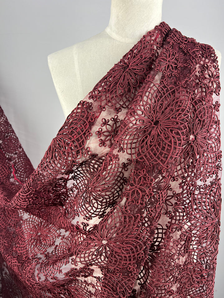 A mannequin draped in intricate Evening Lace - Elizabeth - from Super Cheap Fabrics with elaborate floral patterns. The fabric showcases a combination of complex, delicate designs, providing a rich and ornamental texture against the light background.