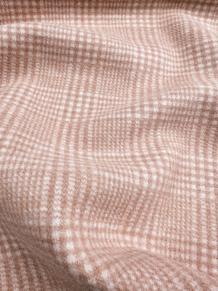 A close-up of a heavyweight fabric with a beige and white checkered pattern. The **Super Cheap Fabrics Wool Flannel - Coral - 148cm** material appears slightly wrinkled, creating gentle waves and shadows that add texture to the image. The design has a warm and cozy appearance.