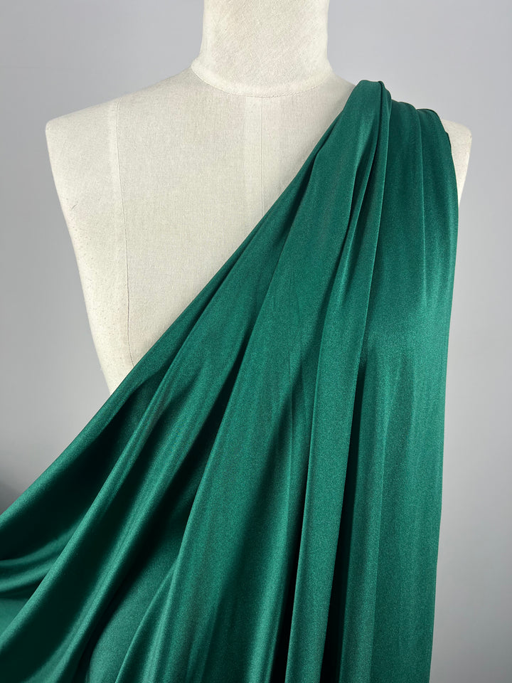 A dress form draped with a piece from the Super Cheap Fabrics "Nylon Lycra - Green Jacket - 150cm" collection, set against a neutral gray background.