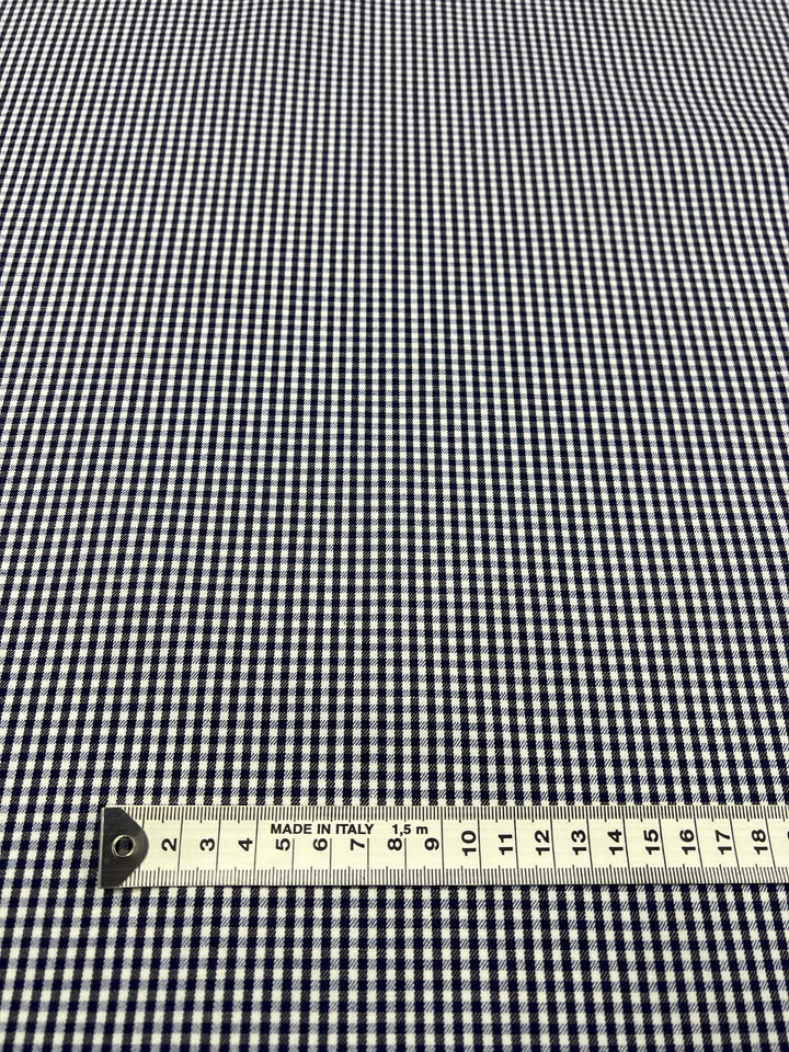 A close-up of the Super Cheap Fabrics Cotton Drill - Mini Gingham, featuring a black and white gingham design woven in a diagonal pattern, with a measuring tape at the bottom displaying centimeters and reading "MADE IN ITALY.