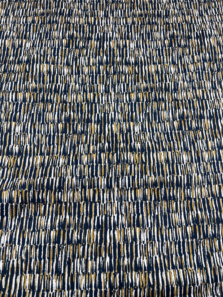 The Cotton Sateen - Eclectic from Super Cheap Fabrics is a textured lightweight fabric featuring densely packed, unevenly spaced vertical and curved lines in navy, white, and gold on a 145cm width, creating an intricate woven look.