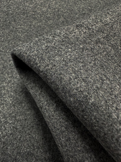 A close-up of Melton Wool - Charcoal Marle - 150cm from Super Cheap Fabrics reveals its soft texture and uniform color. Neatly folded, this heavyweight wool fabric showcases a smooth surface and substantial thickness, perfect for crafting elegant skirts.