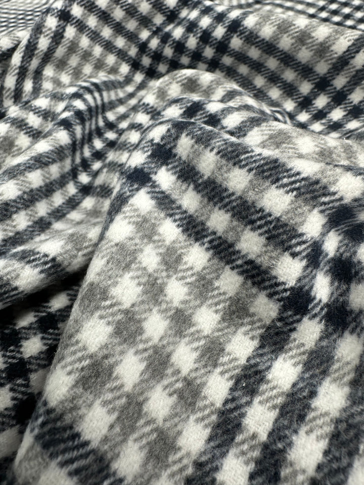 Close-up of a black and white houndstooth patterned fabric, part of our exclusive textile collection from Super Cheap Fabrics. The medium weight Premium Brushed Plaid - Mono - 150cm fabric appears soft and slightly folded, creating shadows and variations in the texture.