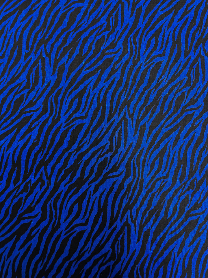 Introducing the Linen Voile - Cobalt Zebra from Super Cheap Fabrics, a captivating fabric pattern showcasing striking cobalt blue zebra-like stripes set against a deep black background. This visually dynamic and textured effect makes it perfect for home decor, while the linen voile material adds breathability for enhanced comfort. The fabric measures 140cm in width.