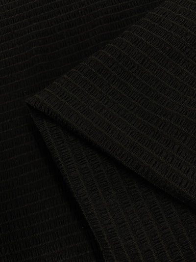 A close-up of the Designer Mesh - Black Rouge from Super Cheap Fabrics showcases its textured black fabric with a ribbed pattern. The 130cm wide, lightweight polyester spandex material appears to be folded, creating a layered effect. The fabric has a subtle sheen, and the vertical ribbing adds dimension to the overall look.