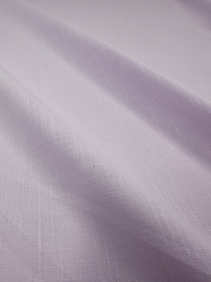 A close-up image of Super Cheap Fabrics' Linen Blend in Orchid Hush, measuring 145cm, showcases its lightweight quality with a subtle woven texture and gentle folds that create soft shadows across the material. Made in Italy.