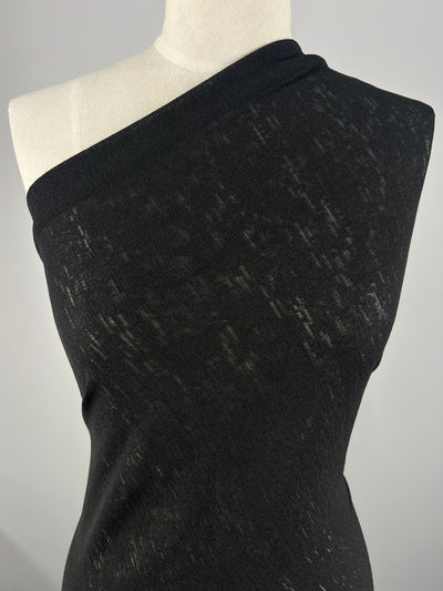 A mannequin displays a black, one-shoulder dress made from Super Cheap Fabrics' Lightweight Slub Jersey. This 100% polyester, textured knit fabric stretches generously for a form-fitting silhouette, elegantly highlighted against a neutral background.