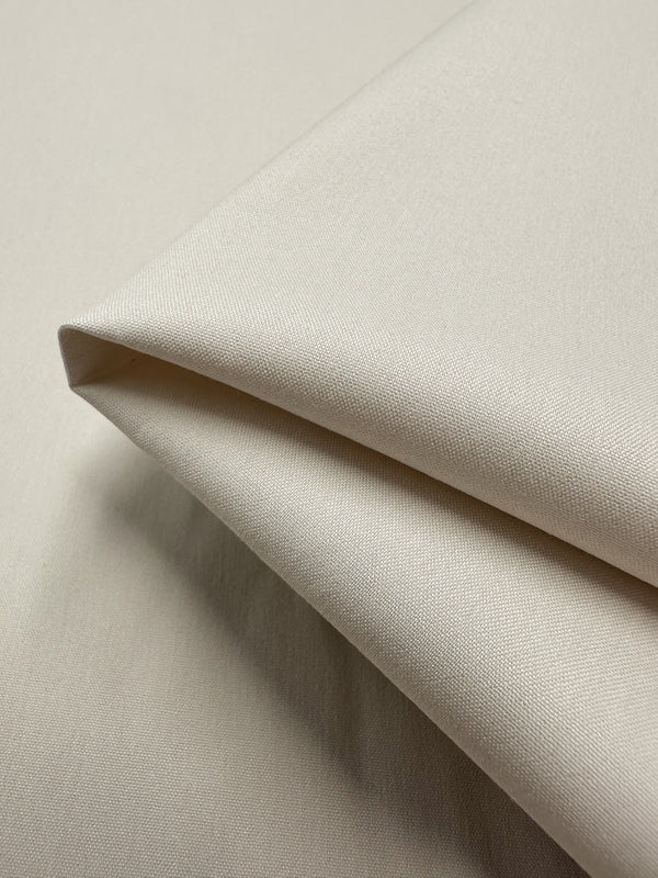 Close-up of a neatly folded piece of Stretch Cotton - Perfectly Pale - 137cm from Super Cheap Fabrics, showcasing its smooth and slightly textured surface. The medium to heavy weight knit fabric features a subtle sheen, suggesting it could be used for crisp fitted dresses, upholstery, or other sewing projects.