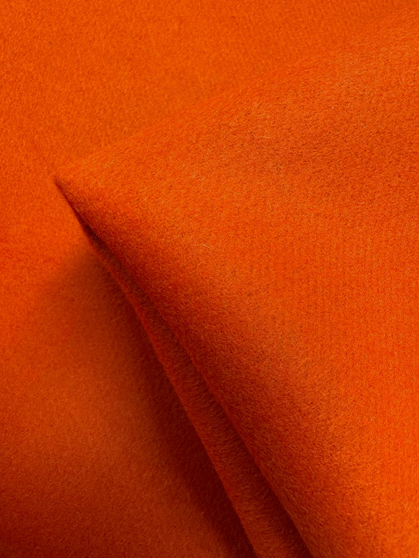 A close-up of Super Cheap Fabrics’ Wool Cashmere - Koi - 150cm reveals its vibrant orange color, cozy warmth, and luxurious softness with a smooth texture and gently folded edges.