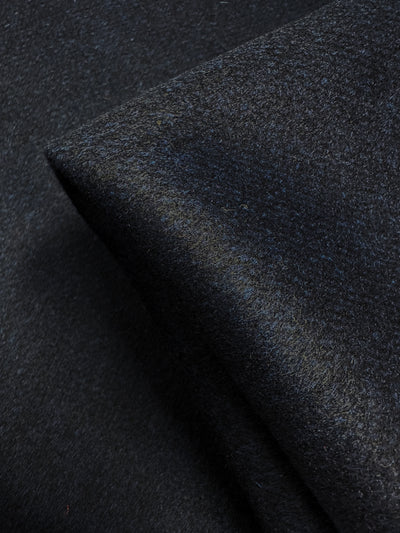 Close-up of Super Cheap Fabrics' Wool Cashmere - Mood Indigo (150cm), a dark, textured fabric with a folded corner that highlights its luxurious softness and subtle sheen.