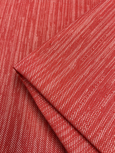 Close-up of Super Cheap Fabrics' Upholstery Twill - Cherry - 147cm with a fine white diagonal stripe pattern in a twill weave. The fabric is shown folded, highlighting the texture and pattern, perfect for furniture upholstery.
