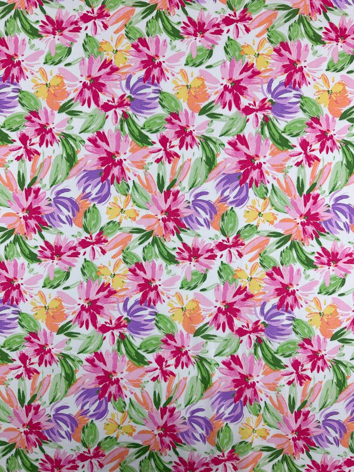 Super Cheap Fabrics’ Printed Linen Blend - Petal Parade (135cm) features a vibrant mix of pink, purple, orange, and yellow flowers with green leaves on white—ideal for lively summer jackets or bright linen upholstery. Evenly distributed floral design.