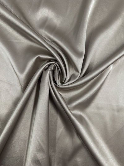 Satin Deluxe - Rock Ridge by Super Cheap Fabrics features a shiny silver-gray luxury fabric with a smooth texture, soft folds, and subtle sheen. Width: 150cm.