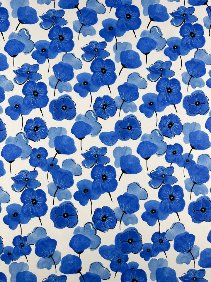 The Printed Cotton - Mykonos - 150cm by Super Cheap Fabrics features a lively artistic design with vibrant blue flowers of varying sizes and shades on thin black stems against a white background, all crafted from natural cotton fibers.