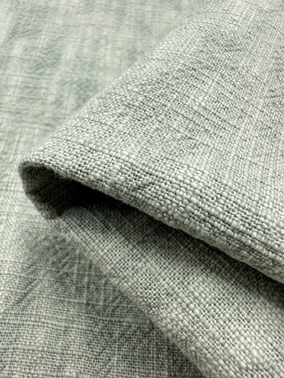 Close-up of a folded piece of heavyweight Basket Dyed Cotton in Sea Mist. This fabric from Super Cheap Fabrics has a woven appearance, highlighting intricate thread details and a subtle grid pattern, making it ideal for upholstery applications. The fabric measures 140cm wide.