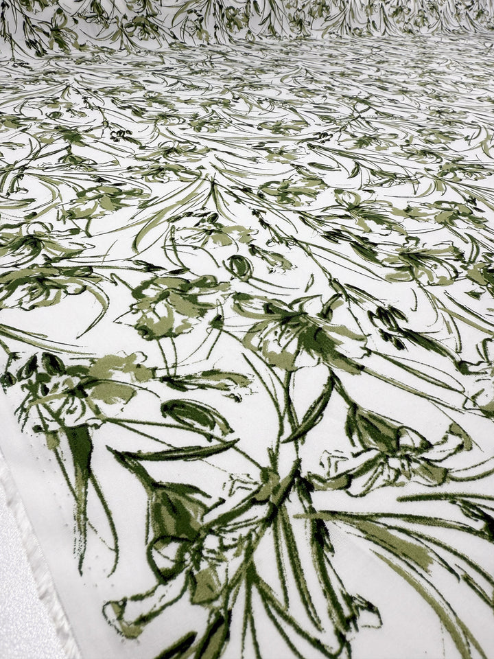 Super Cheap Fabrics' Designer Rayon - Olive Sketch (145cm) features an abstract floral print in shades of green, with sketch-style leaves and flowers arranged in a versatile, repeating pattern.