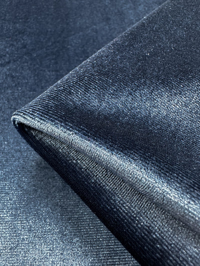 Close-up image of Super Cheap Fabrics' Stretch Velour - Naval Academy, featuring a dark blue medium weight stretch fabric with a smooth, silky reflective surface.