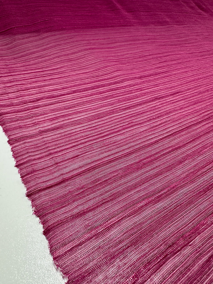 The Metallix Pleat - Hot Pink fabric by Super Cheap Fabrics, measuring 140cm, features a lightweight polyester material adorned with horizontal stripes in shades of pink and purple. It has a slightly shiny surface with a metallic hot pink gradient that transitions from dark to light tones across the fabric.