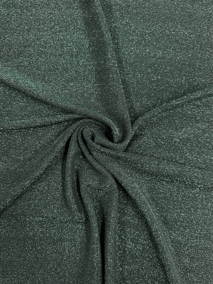 Close-up of the Metallic Lycra - Green Jacket by Super Cheap Fabrics, showcasing its twisted, dark green shimmery fabric with a spiral pattern. The texture appears soft and smooth, reminiscent of elegant dresses, creating a sense of depth and intricate design across its 170cm width.