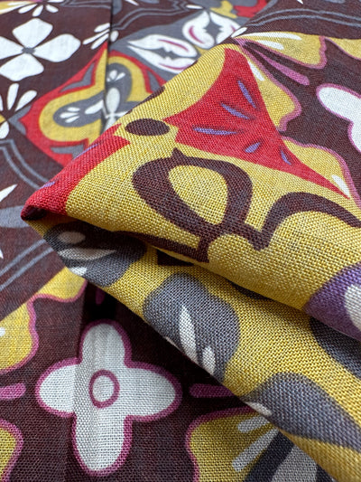 Here's a revised version of the sentence using the given product data:

Close-up of Super Cheap Fabrics' Linen Blend - Mosaic - 145cm, showcasing vibrant floral and abstract designs in red, yellow, white, and brown hues. The breathable linen blend fabric is folded to reveal its visible textures and vibrant details, highlighting its lightweight appeal.