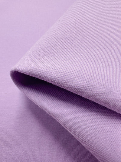 Close-up of the Cotton Lycra - Orchid Bouquet - 170cm by Super Cheap Fabrics, highlighting its ribbed texture and smooth light purple surface with a folded edge.