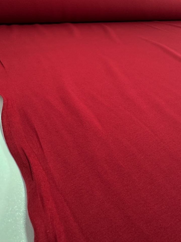 A close-up of Super Cheap Fabrics' Cotton Lycra - Karanda Red - 165cm reveals its soft, slightly textured material with even lighting showcasing the rich color and fine details.
