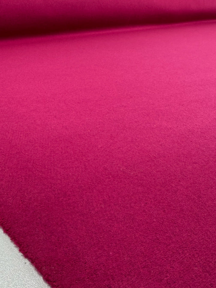 A close-up view of Super Cheap Fabrics' Wool Cashmere - Vivacious - 148cm, showcasing its bright pink premium material spread smoothly on a flat surface.