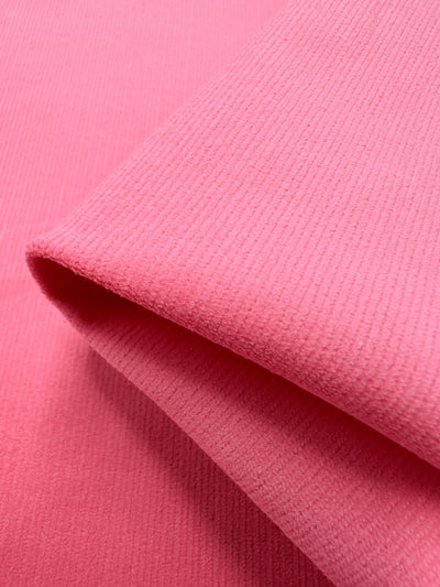 Close-up image of Super Cheap Fabrics' Micro Wale Corduroy in Camellia Rose, 147cm wide, showcasing its smooth ribbed texture and vibrant color. Ideal for cozy winter clothing.