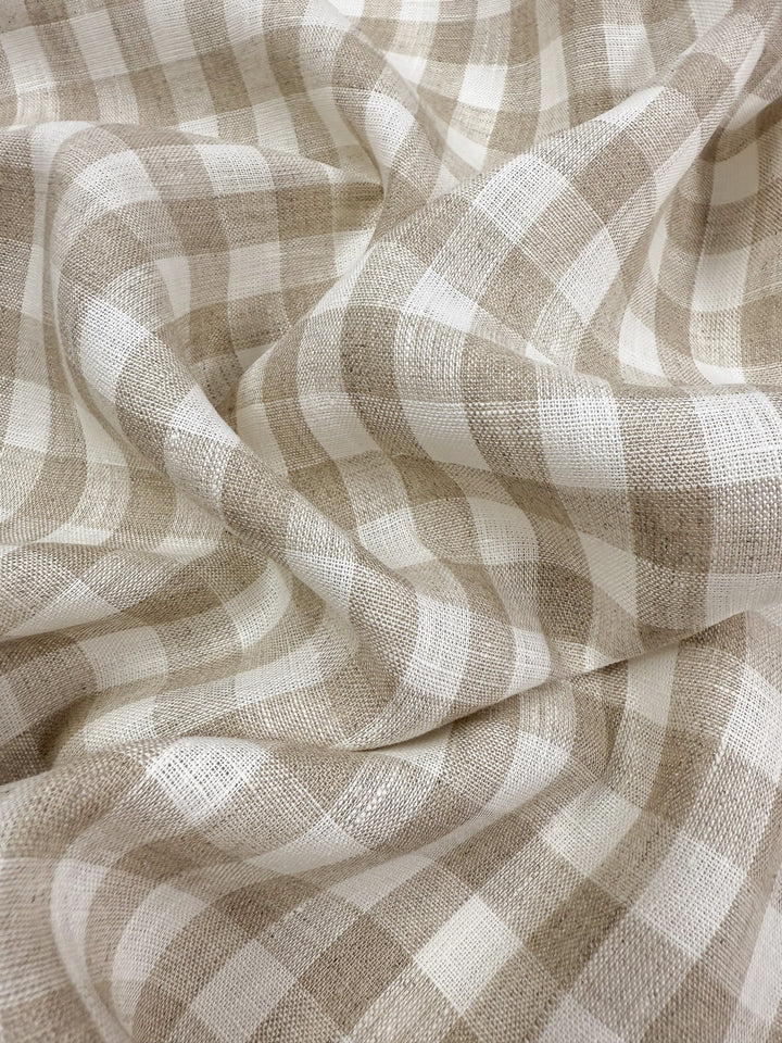 Super Cheap Fabrics’ Pure Linen - Oatfield Check (140cm) is a beige and white gingham linen with a checkered pattern, showcasing soft folds and lightweight texture—sustainable and elegant for any project.
