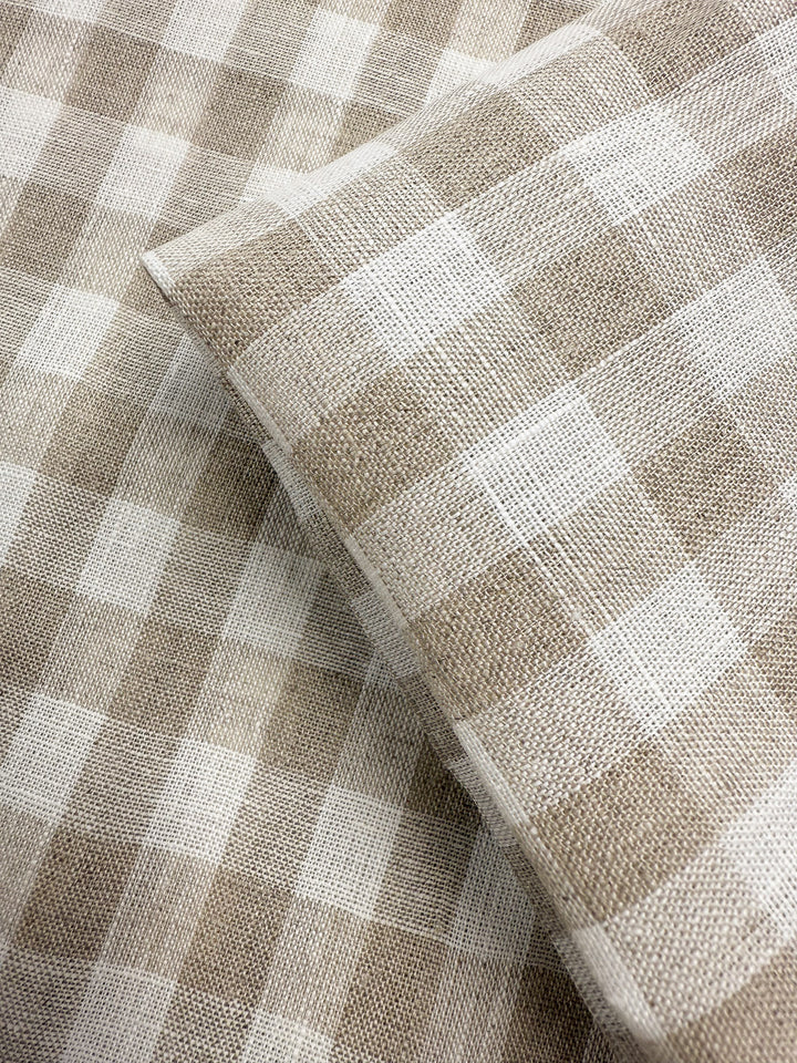 Close-up of Super Cheap Fabrics’ Pure Linen - Oatfield Check (140cm), featuring beige and white gingham with a woven texture, shown as two lightweight linen pieces overlapping diagonally.