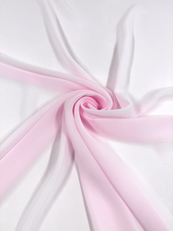 Hi-Multi Chiffon - Calcite by Super Cheap Fabrics (150cm) is displayed in soft, light pink and white folds spiraling outward on a white surface, highlighting the airy elegance of this lightweight sheer fabric.