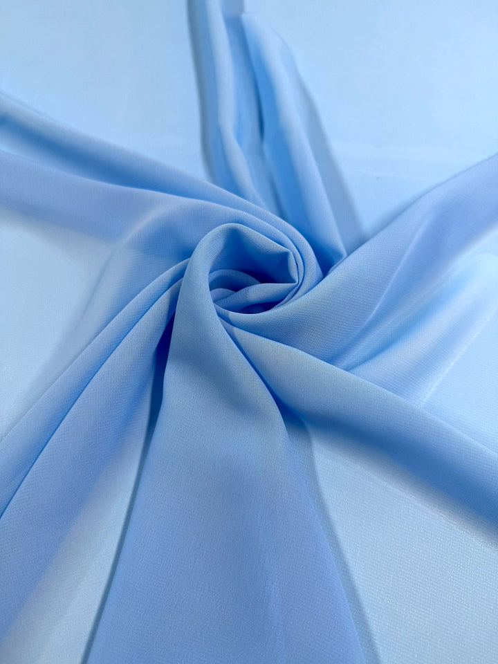 Hi-Multi Chiffon - Blue Grotto by Super Cheap Fabrics features light blue polyester in a spiral pattern, with soft, sheer folds radiating outward on a smooth surface. Width: 150cm.