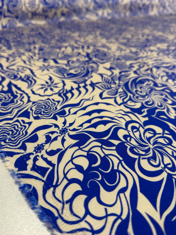 Close-up of Mercerised Rayon - Cobalt Whirl by Super Cheap Fabrics, featuring blue floral and abstract patterns on lightweight, breathable rayon. The fabric, 150cm wide, is laid flat to showcase its textured surface and intricate design.
