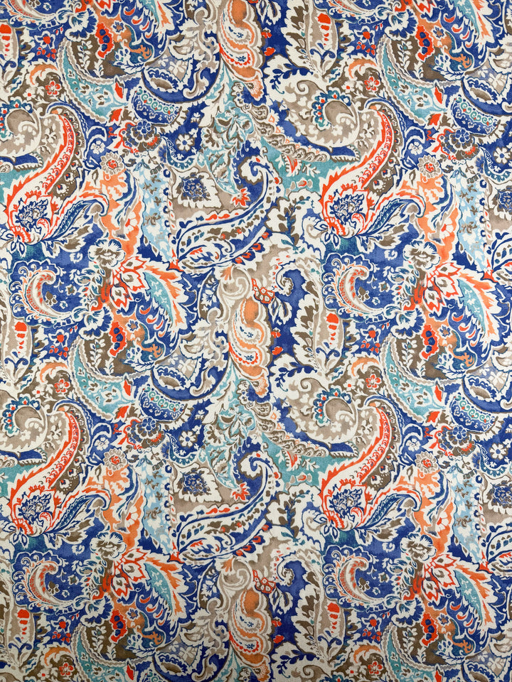 The Mercerised Rayon - Paisley Fusion (150cm) from Super Cheap Fabrics features a lightweight fabric with a colorful paisley pattern in blue, teal, orange, and beige, showcasing swirling floral and leaf designs in symmetrical repeats.