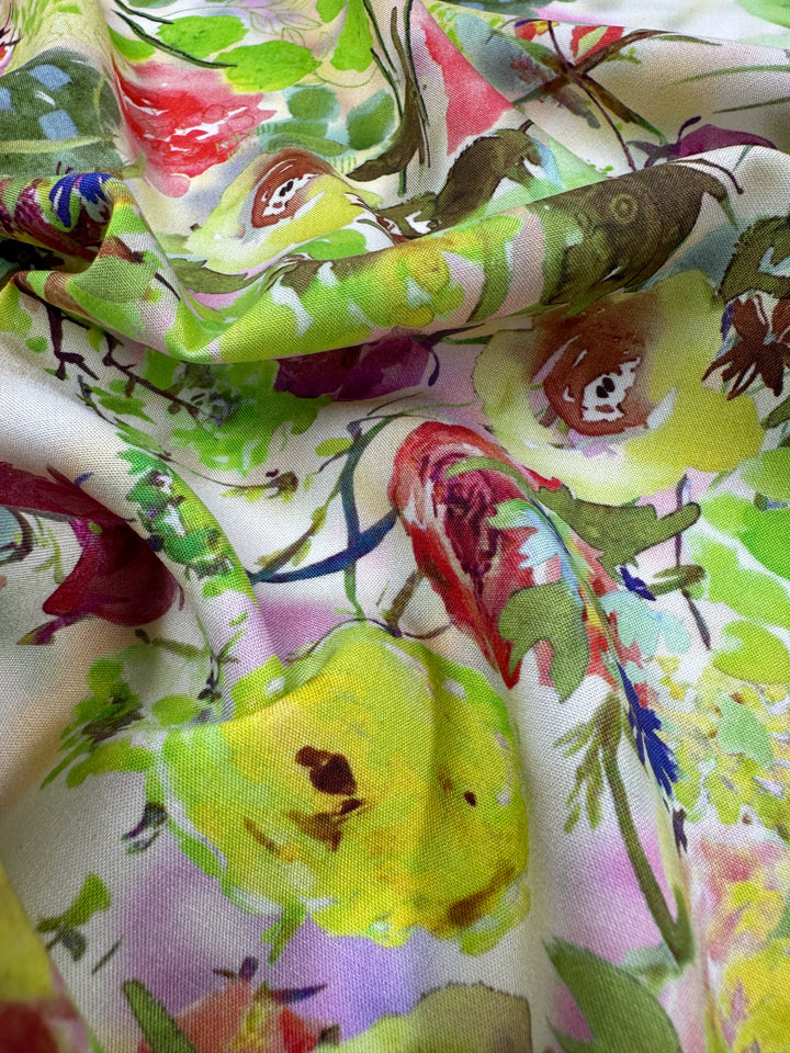 Close-up of Super Cheap Fabrics' Designer Rayon - Sierra, 145cm, displaying a vibrant floral pattern with yellow, pink, and red flowers alongside green leaves. This versatile fabric is soft and drapes gently, highlighting its intricate design.