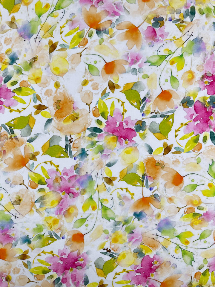 The Designer Rayon - Jesse by Super Cheap Fabrics features a vibrant floral pattern with pink, orange, and yellow watercolor-style flowers and green leaves on white. This abstract design offers a lively, cheerful feel, making it a versatile choice for various projects. Width: 145cm.