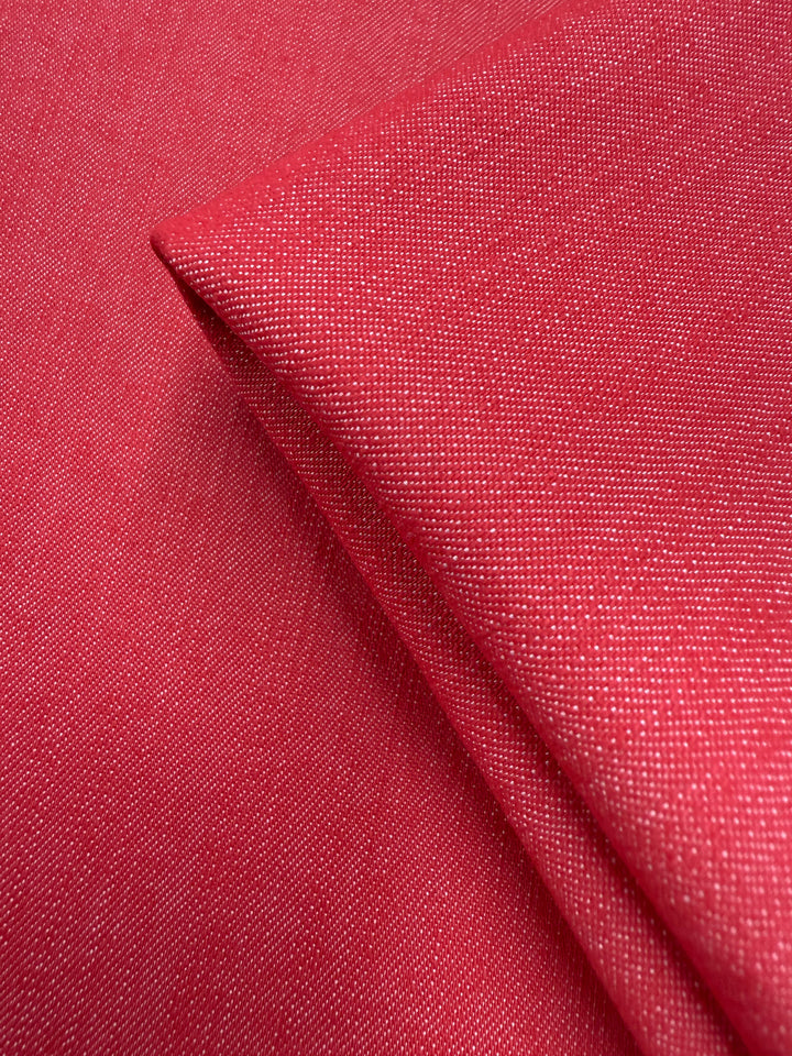 Close-up of Super Cheap Fabrics' Denim - Hibiscus - 150cm, featuring textured pink 100% cotton with a visible weave and a neatly folded corner over a flat surface.