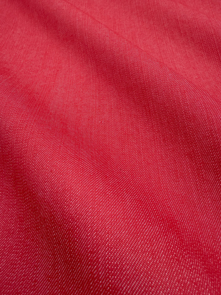 Close-up of Super Cheap Fabrics' Denim - Hibiscus - 150cm, featuring red 100% cotton fabric with visible diagonal weave and gentle folds, creating a soft, slightly wavy look similar to medium-weight denim.