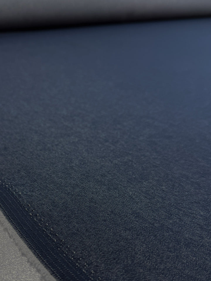 Close-up of Super Cheap Fabrics' Denim - Classic - 150cm, showing the smooth texture and fine stitching on this dark blue 100% cotton denim fabric.